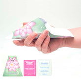 A hand holding a disposable pee funnel with floral patterns, alongside images of the product and its individually packaged components including a feminine wet wipe and a sanitizing wipe.